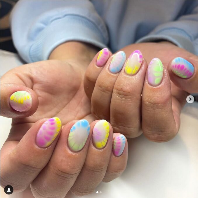 Colorful pastel tie-dye nails with yellow, pink, blue, and green accents