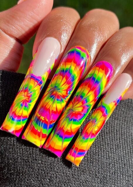nails with a vibrant tie-dye design in neon rainbow shades