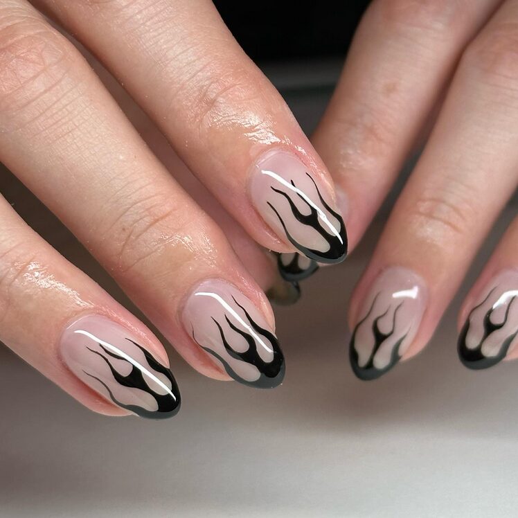 Black flame tip nails with gothic fiery design.