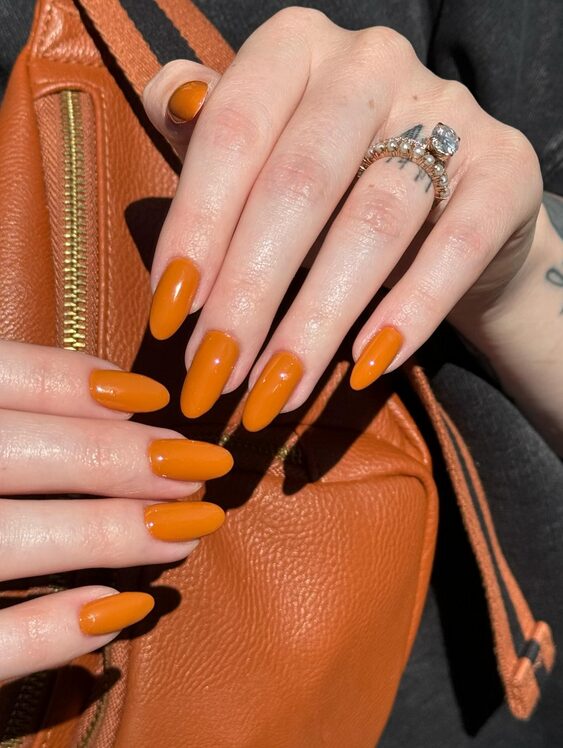 Burnt orange solid color manicure on almond-shaped nails
