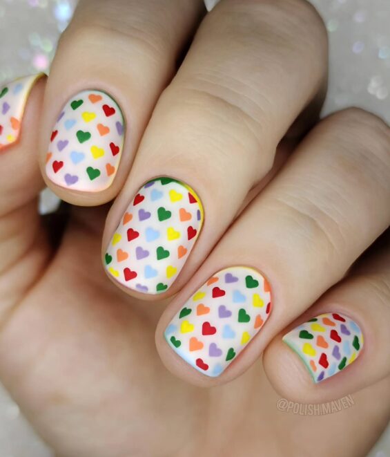 clear nails with scattered colorful heart confetti accents