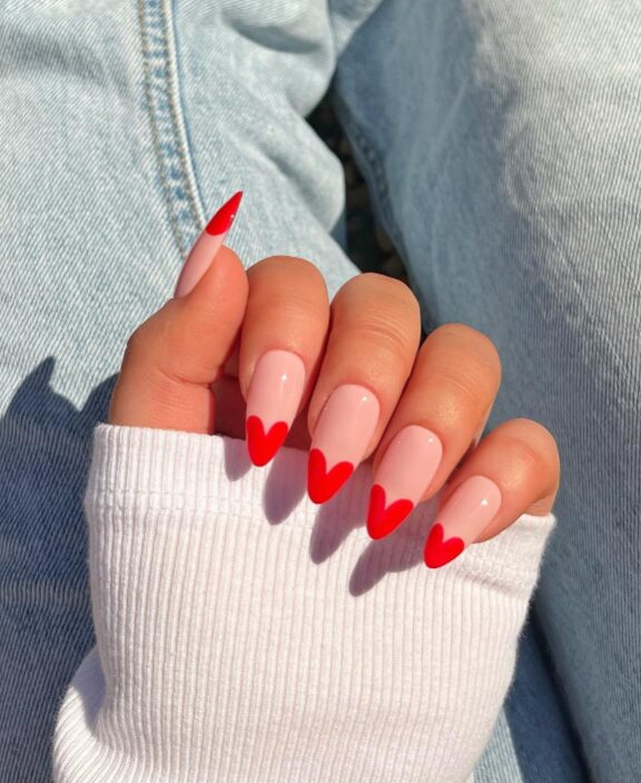 French manicure with red heart-shaped tips on nude nails