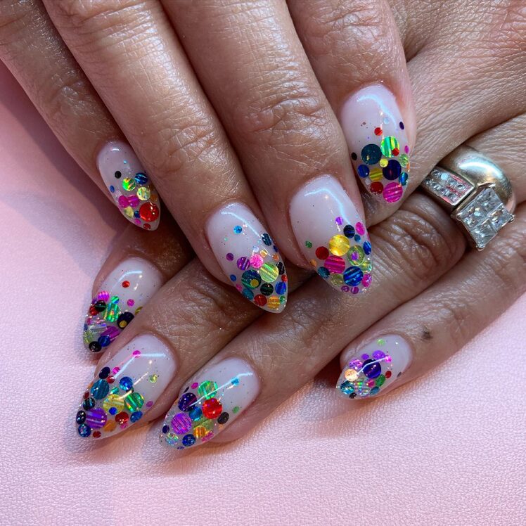 Nude nails with bright multicolor confetti glitter covering the tips