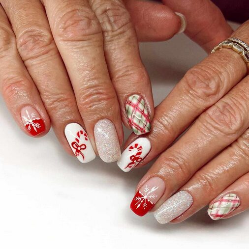 holiday motif nails featuring tiny snowflakes, candy canes, and stars on a glossy festive manicure.