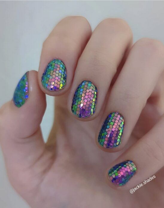 short nails covered in multicolor holographic hexagon sequins