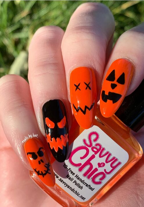 Orange nails with jack-o’-lantern face nail art