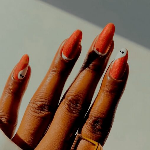 Close-up of sparkling orange nails with a glossy, glittery finish
