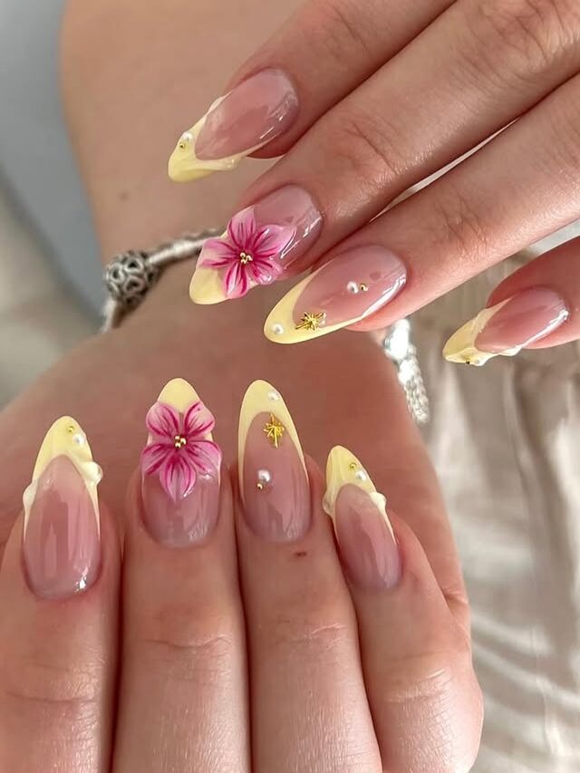 Almond-shaped spring nails with soft yellow French tips and pink floral nail art on a glossy nude base