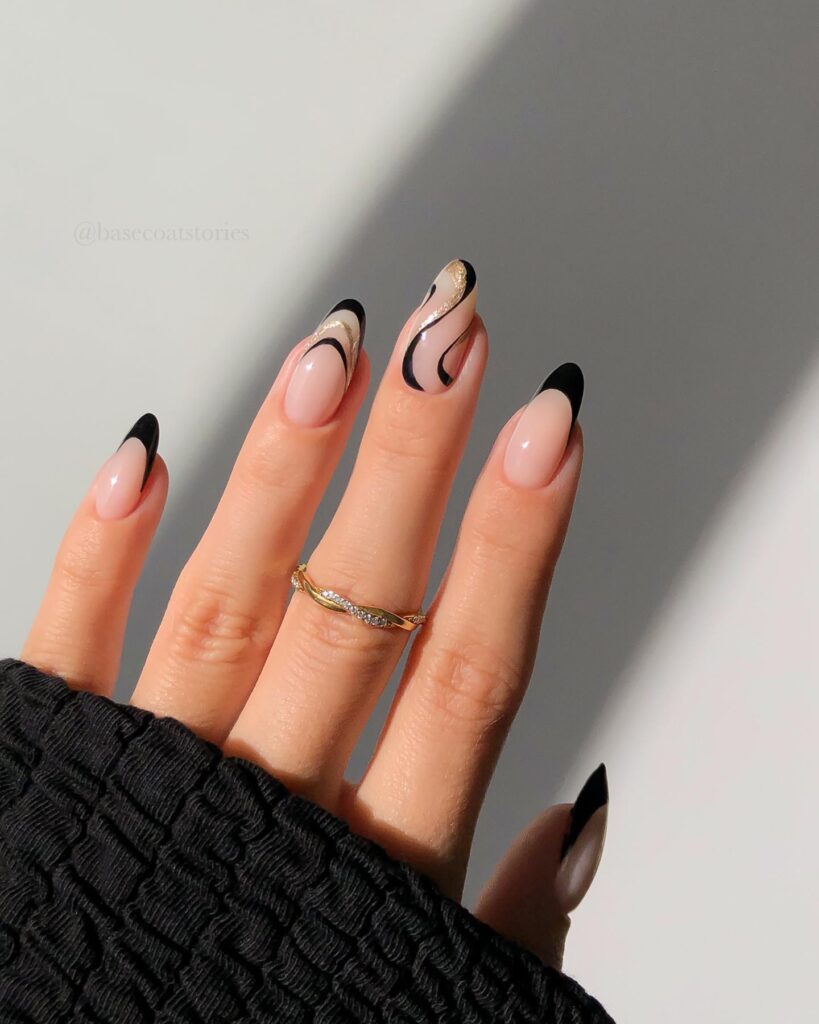 nude nails with black French tips and abstract black and gold swirl nail art