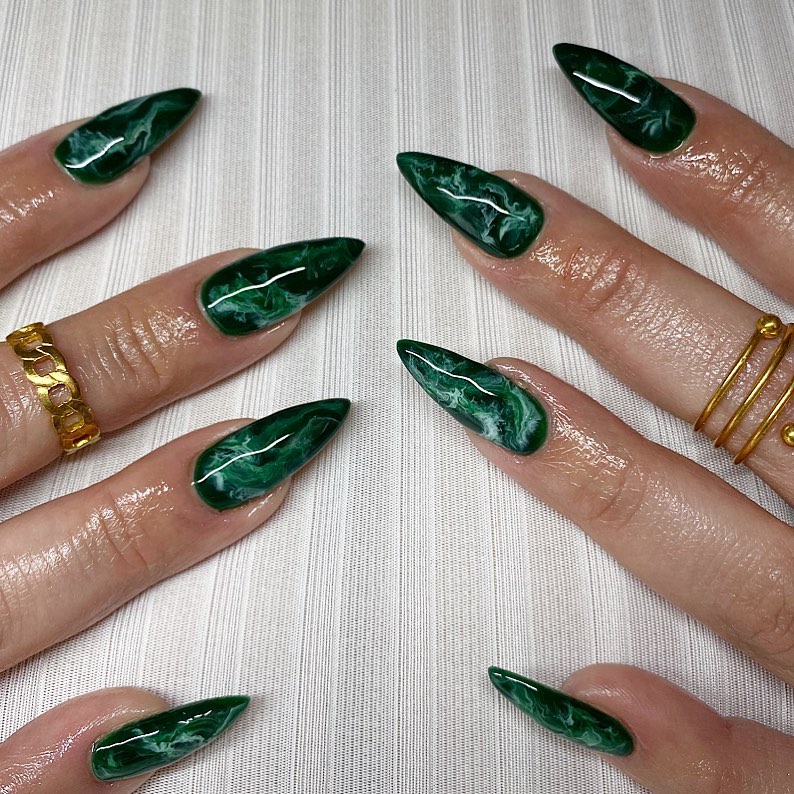 dark green stiletto nails with marble design and elongated pointed tips