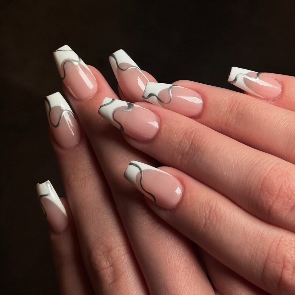 nails with white French tips featuring hand-painted black bow and lace vine nail art