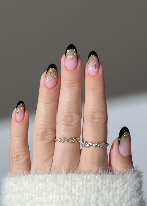 Black French tip nails with gold star accents