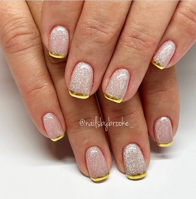 Short glitter nails with thin gold French tips
