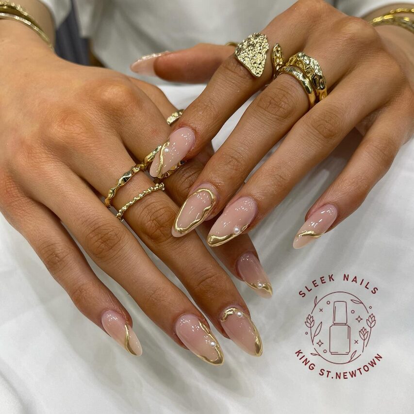 Nude almond nails with elegant gold French tips and delicate gold line accents