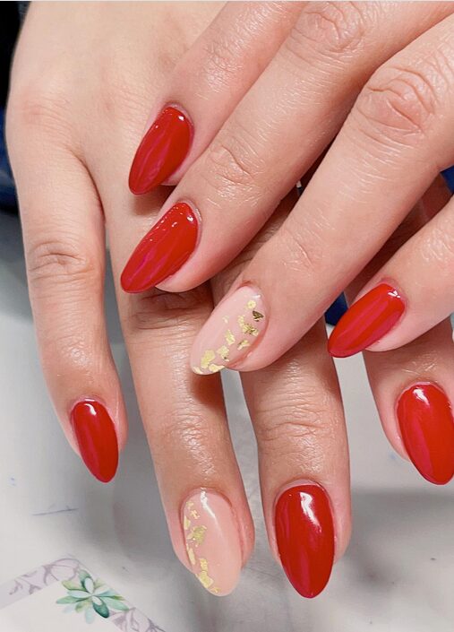 red almond nails with nude accent nails and gold leaf details