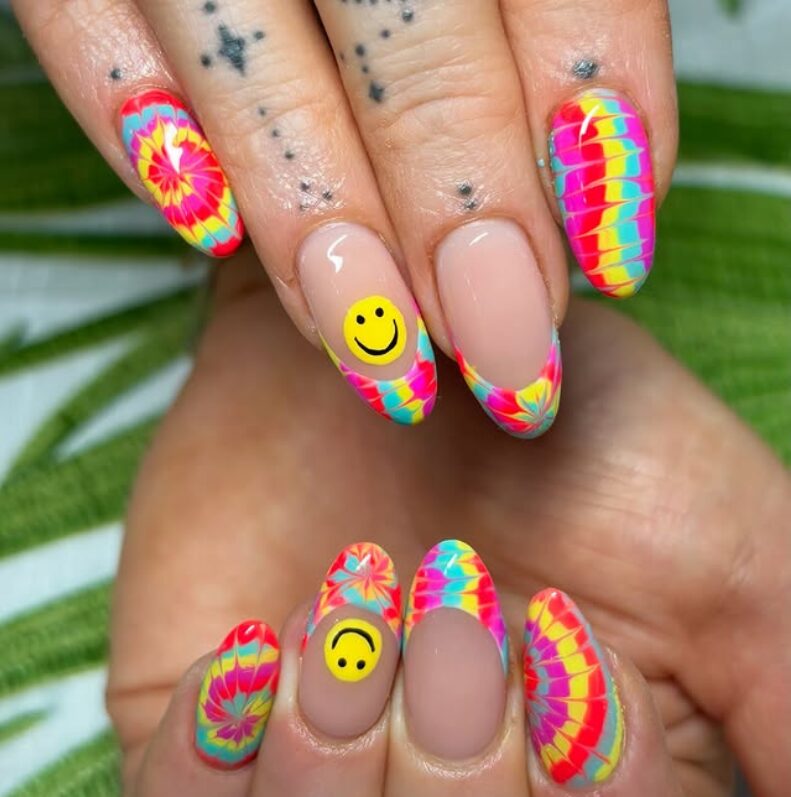 Bright tie-dye French tip nails with smiley face accents