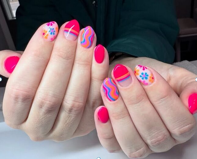 Bright pink mismatched nails with floral designs and colorful swirl patterns