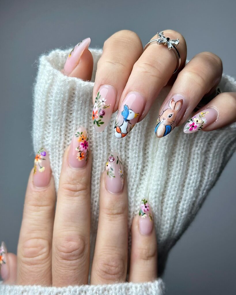 Sheer nude almond nails with Peter Rabbit and wildflower art