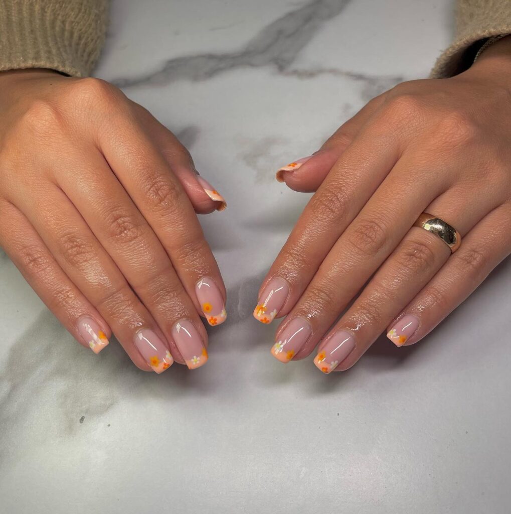 Nude nails with coral daisy French tips