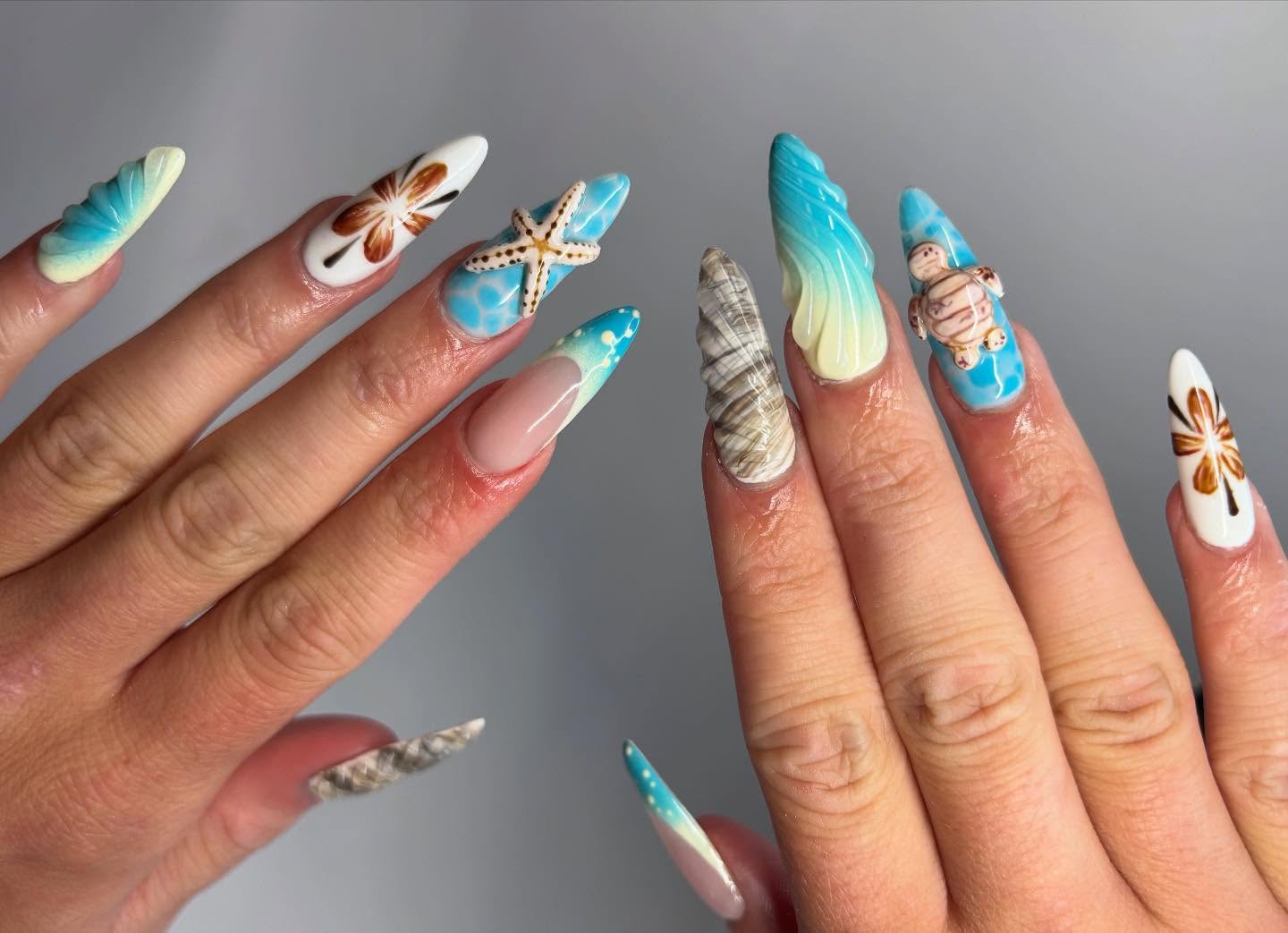 Long stiletto nails with a real dried starfish, sculpted shells, sea turtles and tropical flowers on a turquoise base