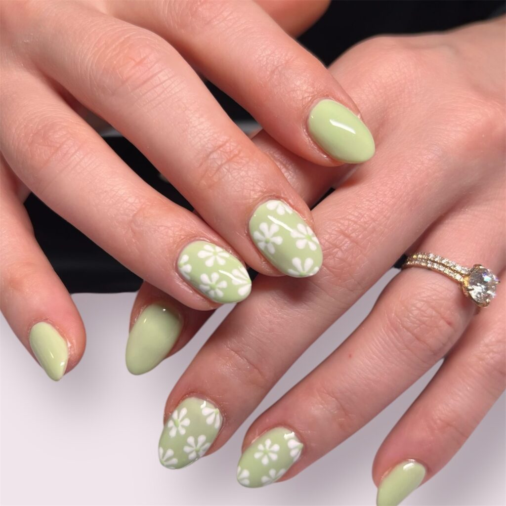 Light pistachio green nails with white daisy flower accent nail art
