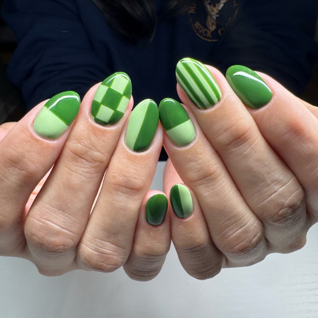Short round nails with mixed green geometric patterns including checkerboard and stripes

