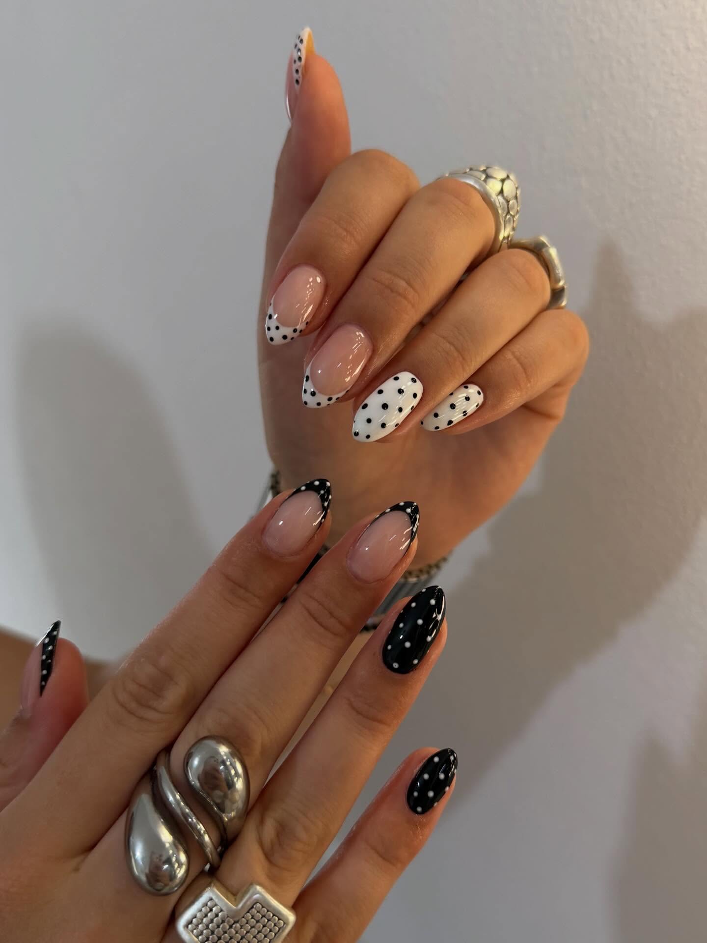 Almond nails with alternating black and white polka dot French tips