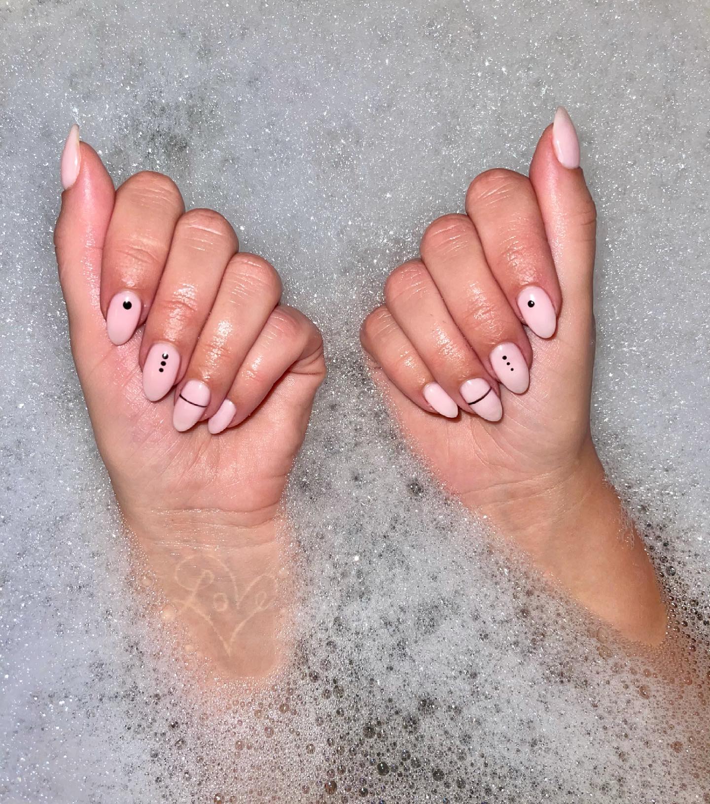 Baby pink matte almond nails with tiny black dot and line detail