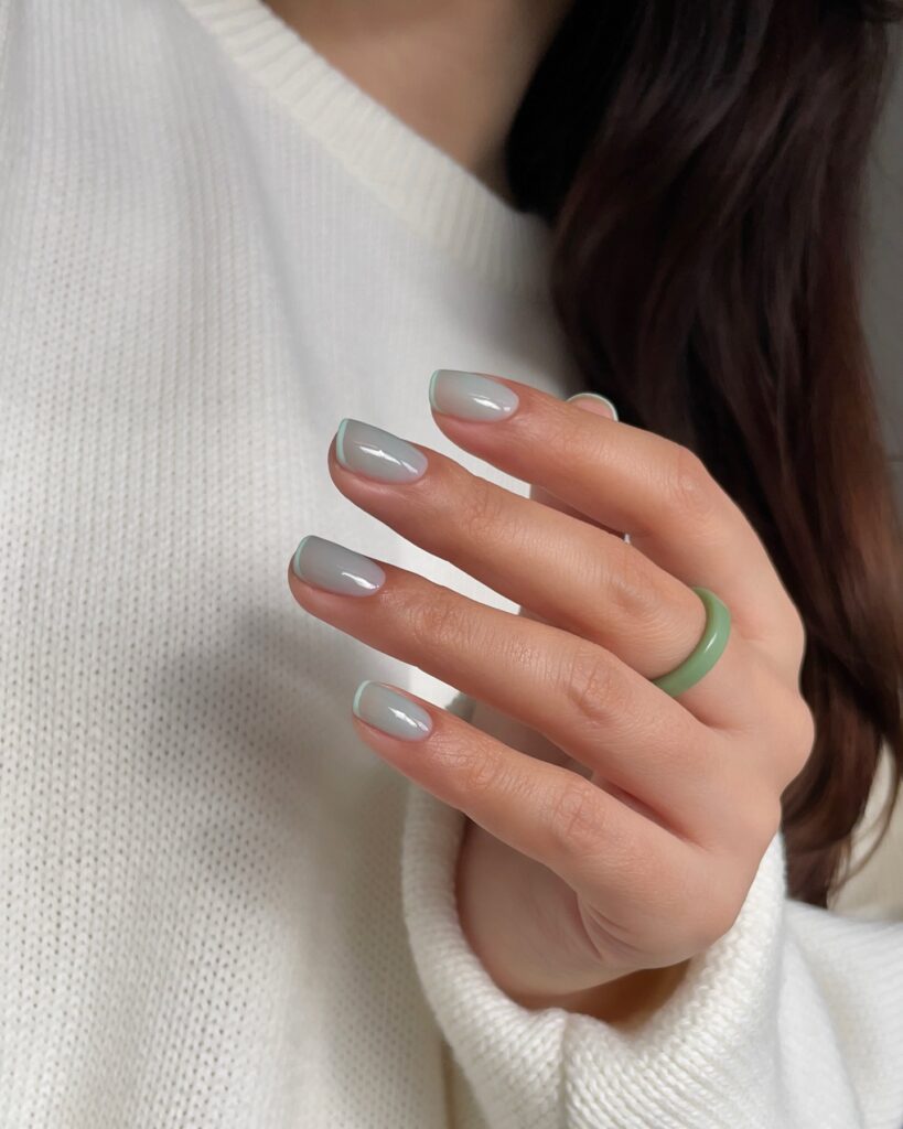 Short square nails with milky taupe base and barely there mint green French tip line

