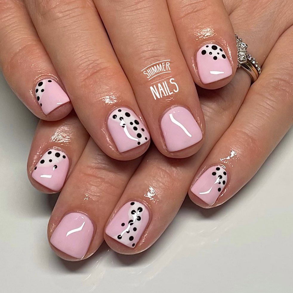 Short square blush pink nails with black dot clusters and white swirl detail