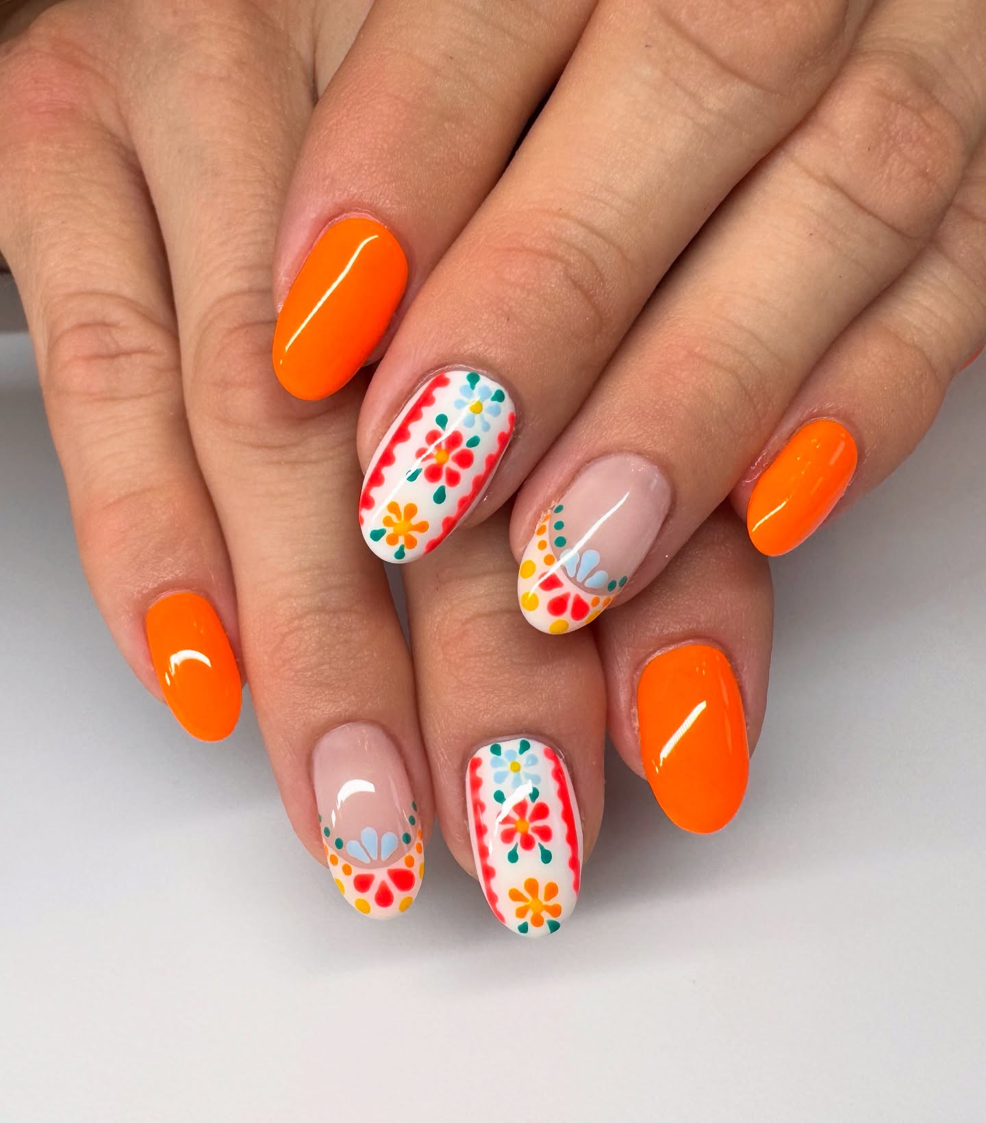 Bold orange almond nails with colourful folk art floral accents
