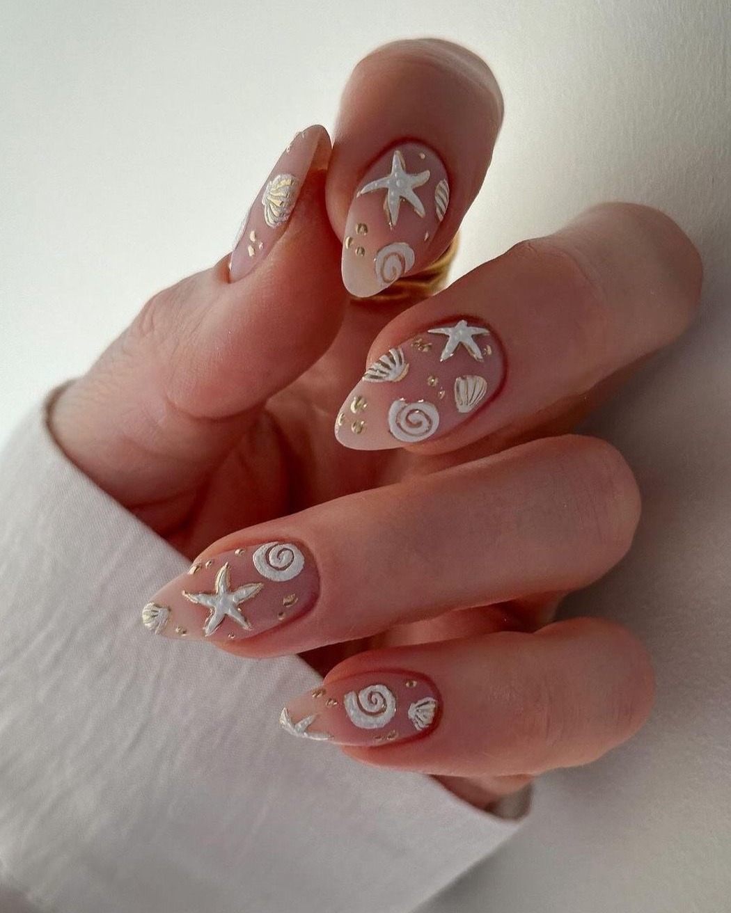 Dusty rose matte nails with raised white and gold starfish, shells and spirals