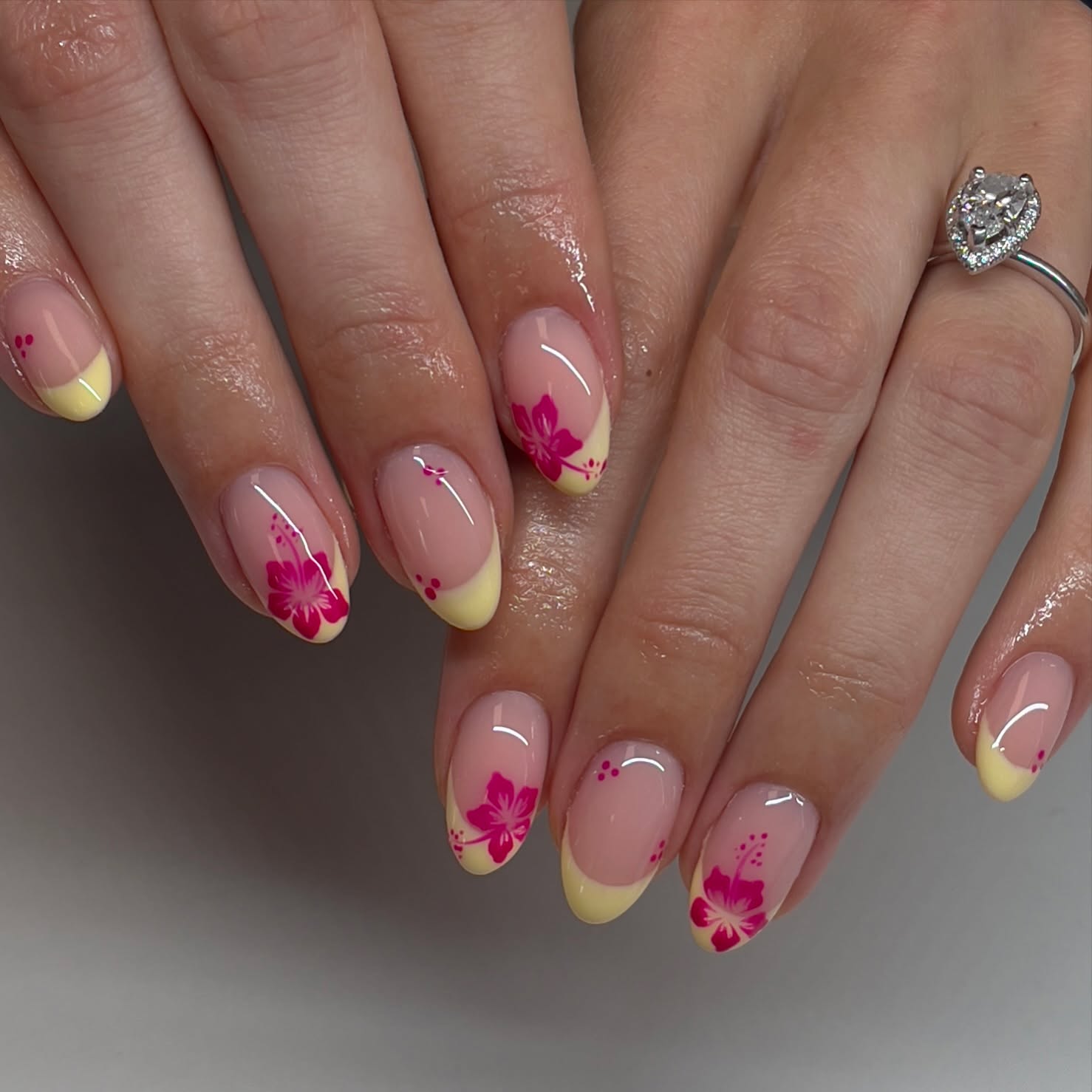 Nude almond nails with yellow French tips and pink hibiscus