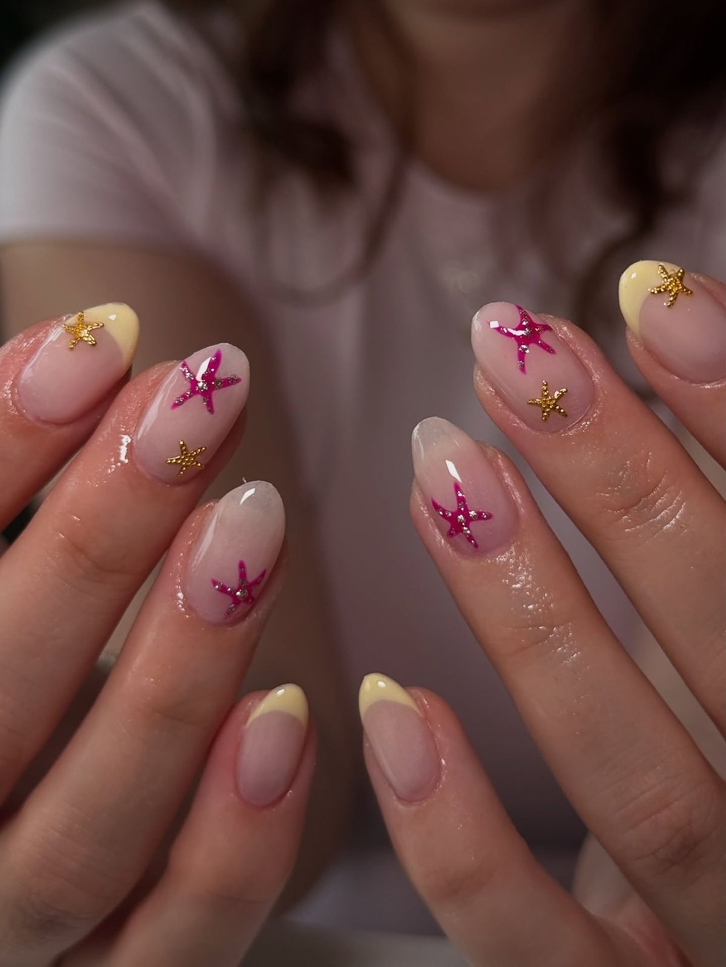 Butter yellow French tips with hot pink glitter and gold starfish on sheer nails