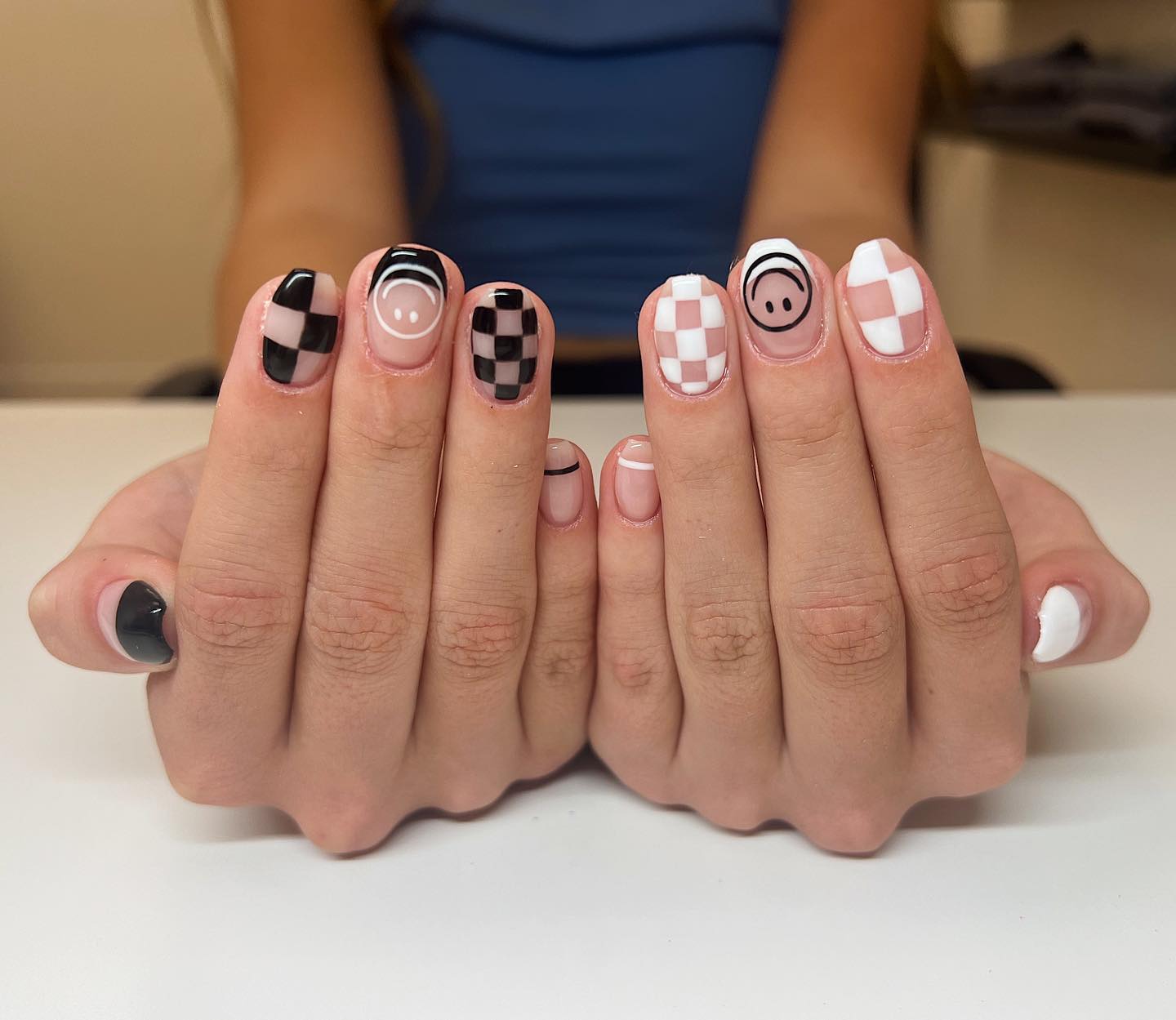 Black and white checkerboard nails with smiley face accent