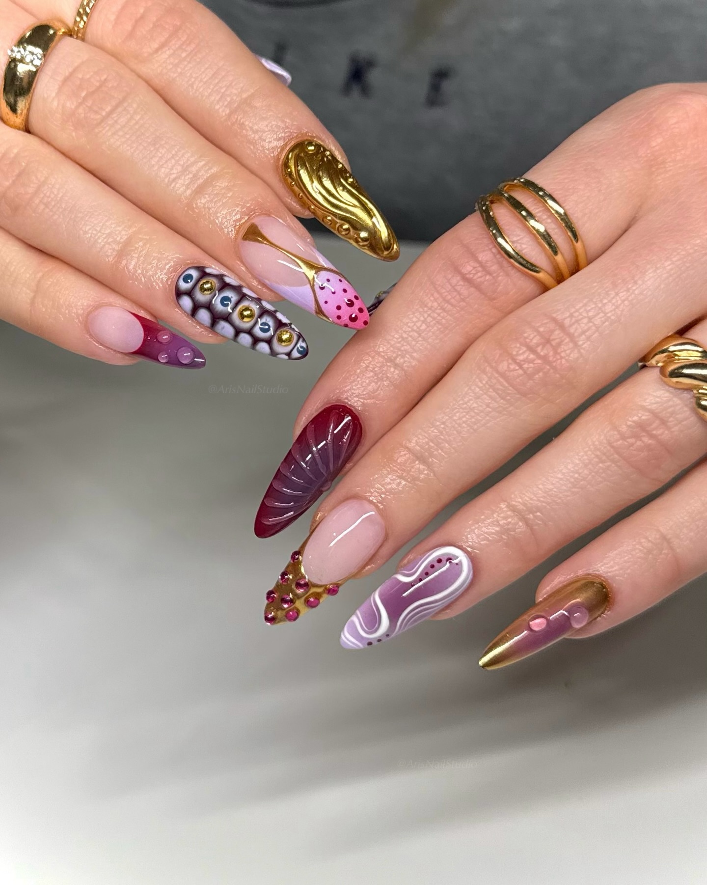 Dark burgundy almond nails with 3D gold and swirl art
