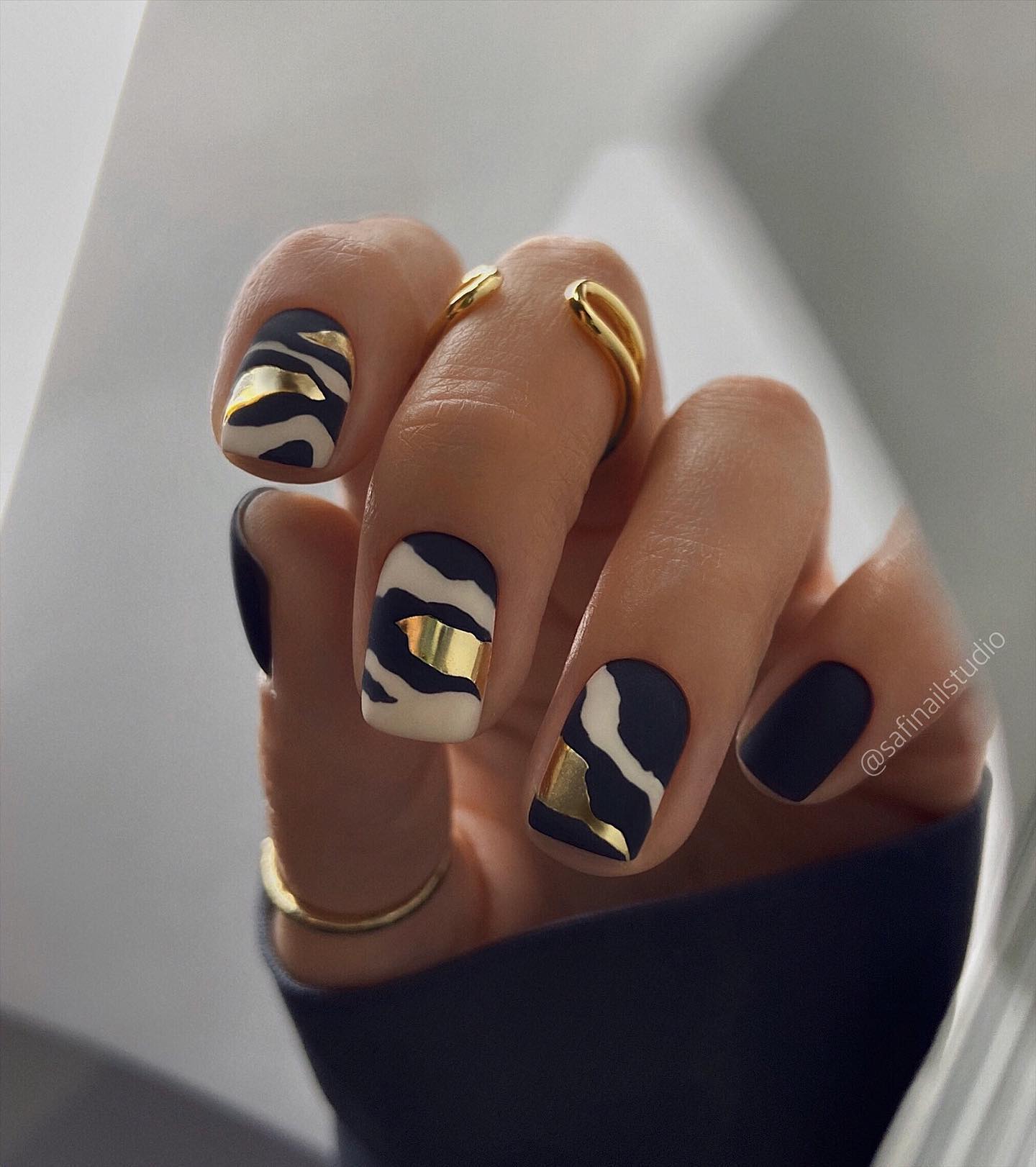 Dark navy and black nails with zebra print and gold foil accents