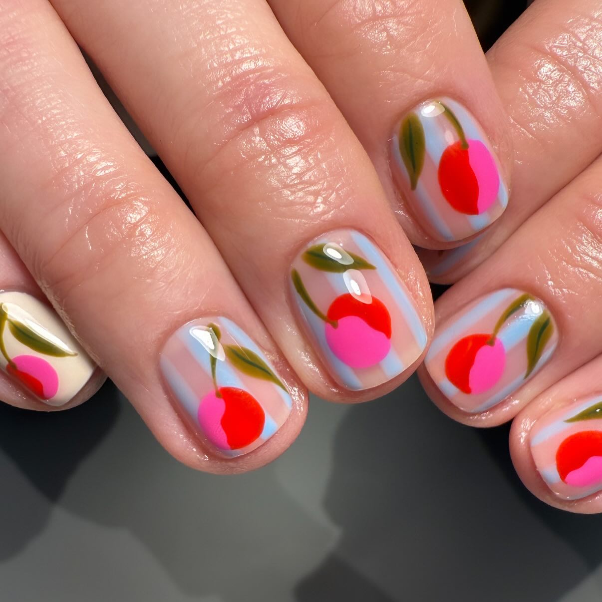 Peach fruit print nail art on a blue stripe base