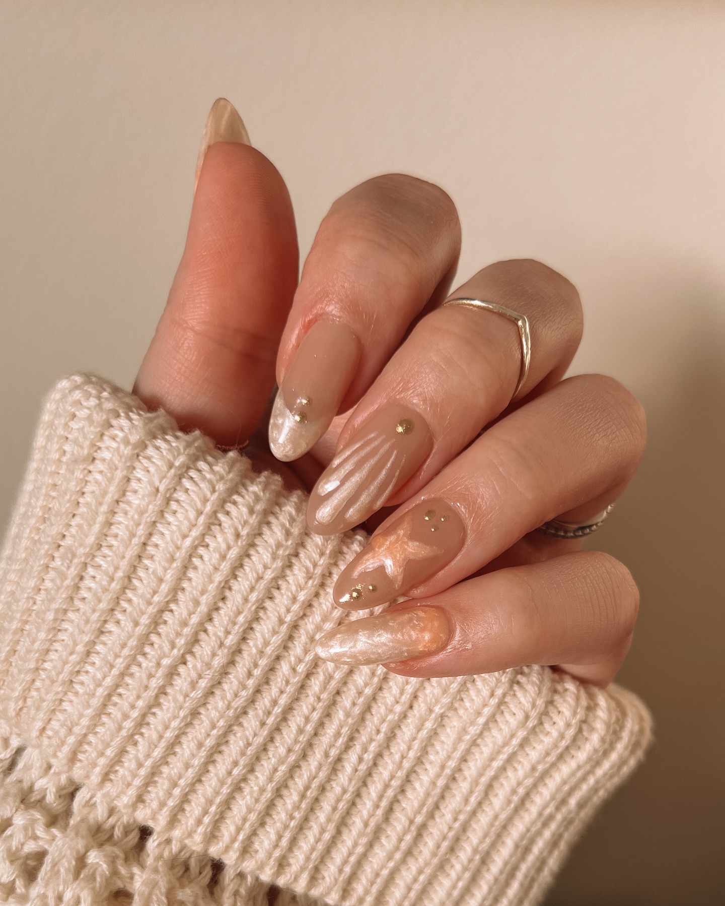 Glazed nude almond nails with peach marble and gold fleck accents