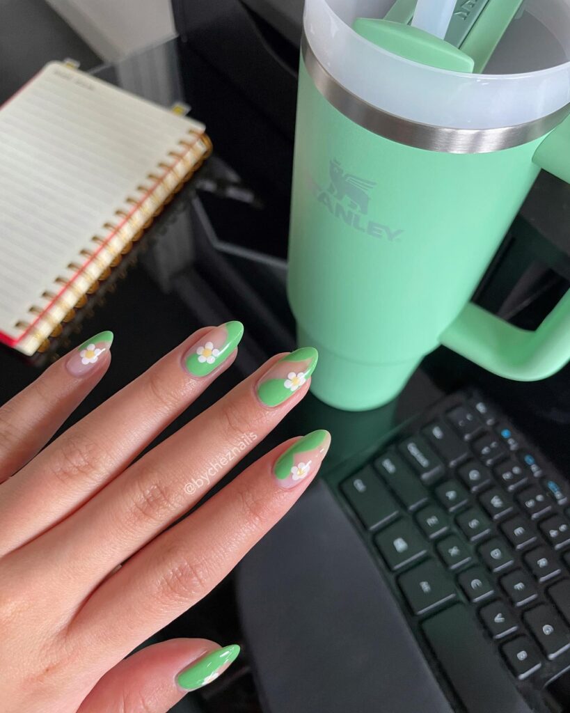 Almond nails with bright green color block French tips and small white daisy flower details
