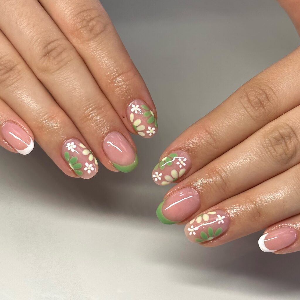 Short nails with green French tips and white daisy floral nail art on nude base
