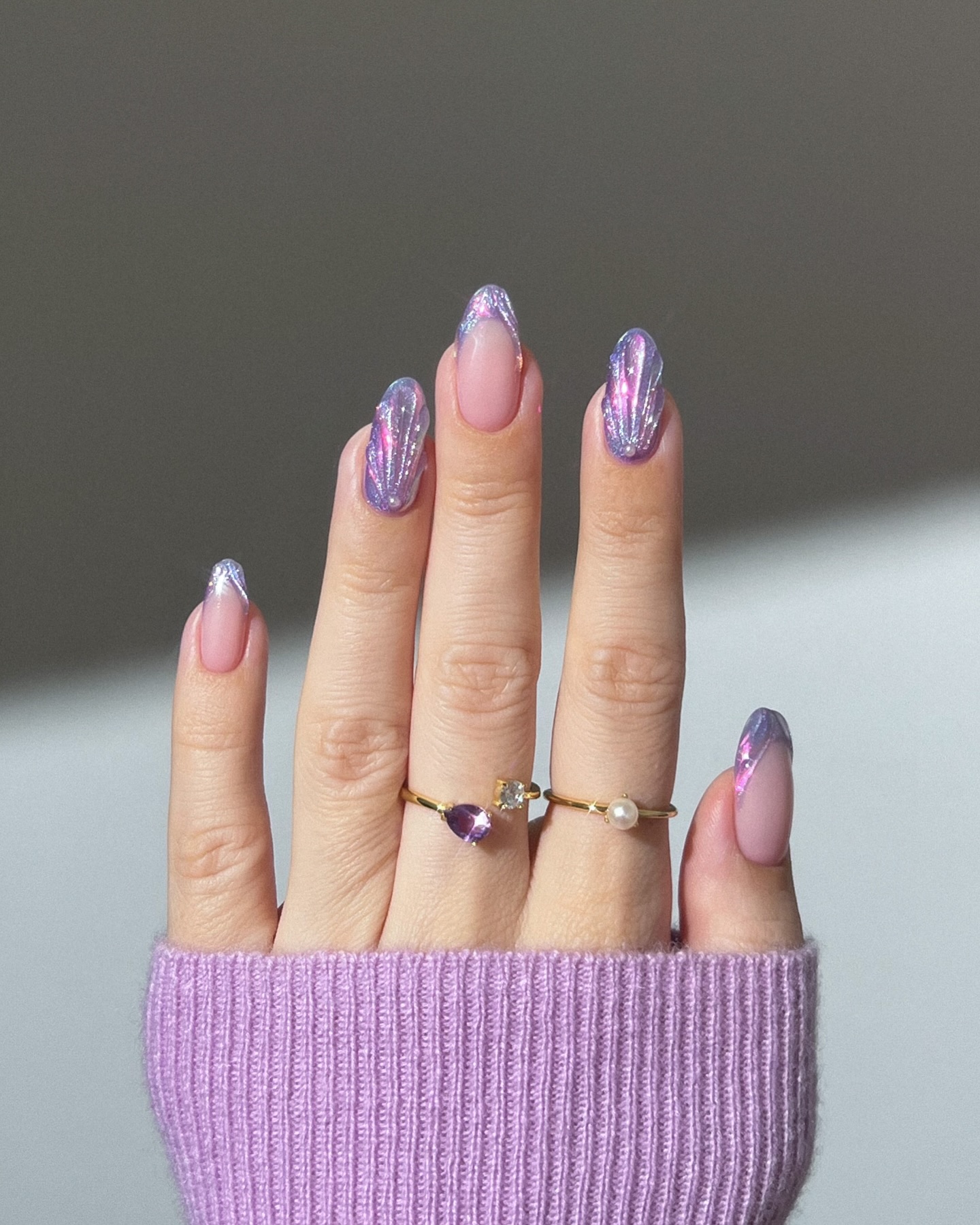 Nude almond nails with iridescent purple seashell glitter tips