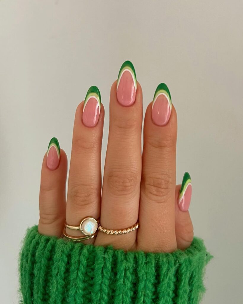 Long almond nails with layered dark and light green French tips on a soft pink base

