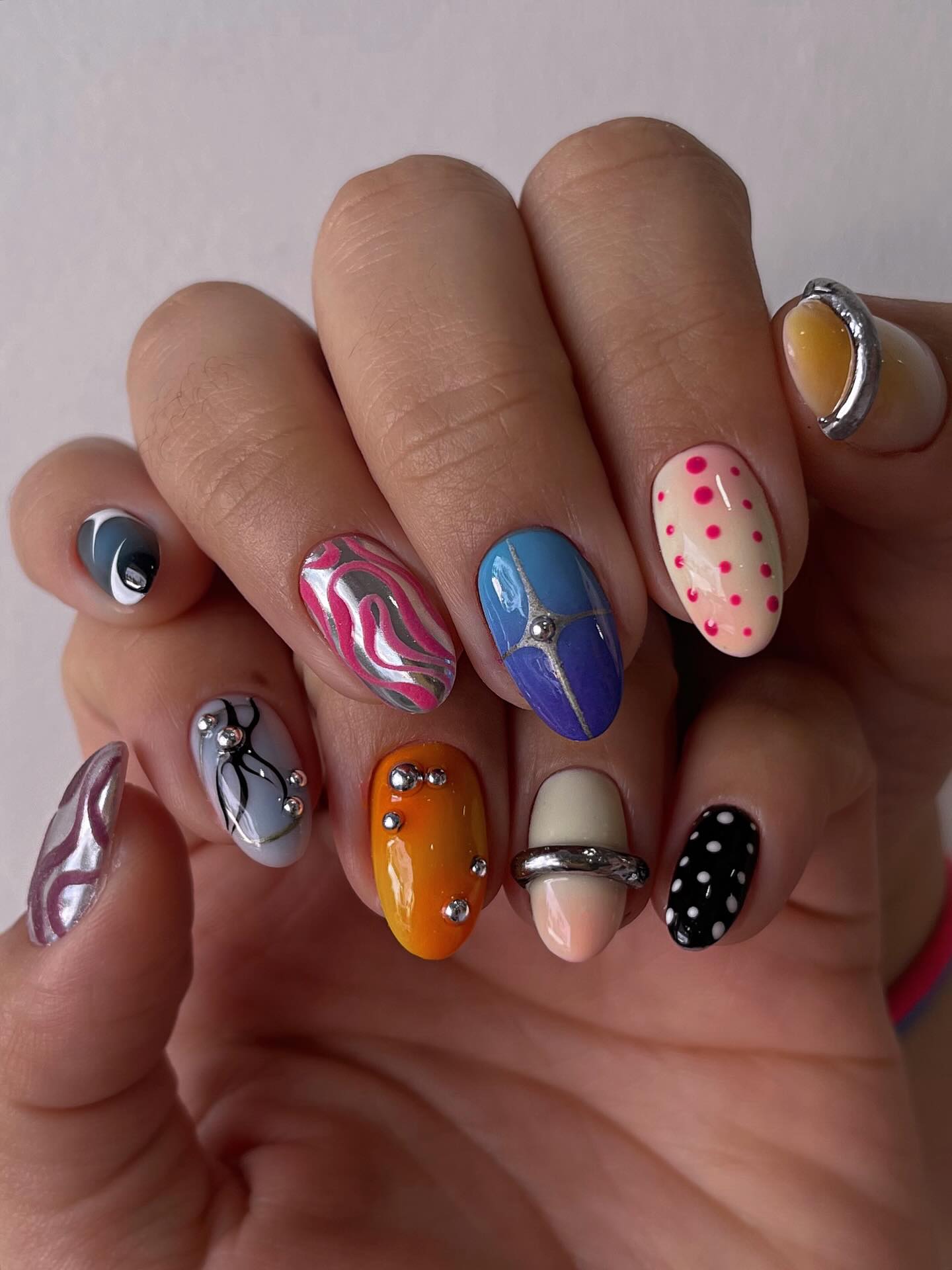 Bold maximalist almond nails with chrome accents and rhinestones