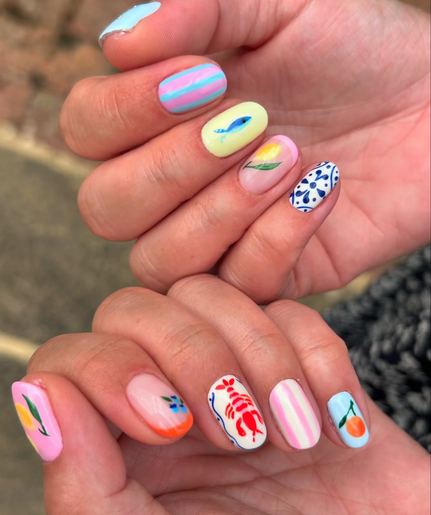 Short nails with blue and white tiles, stripes, lobster, citrus and floral designs