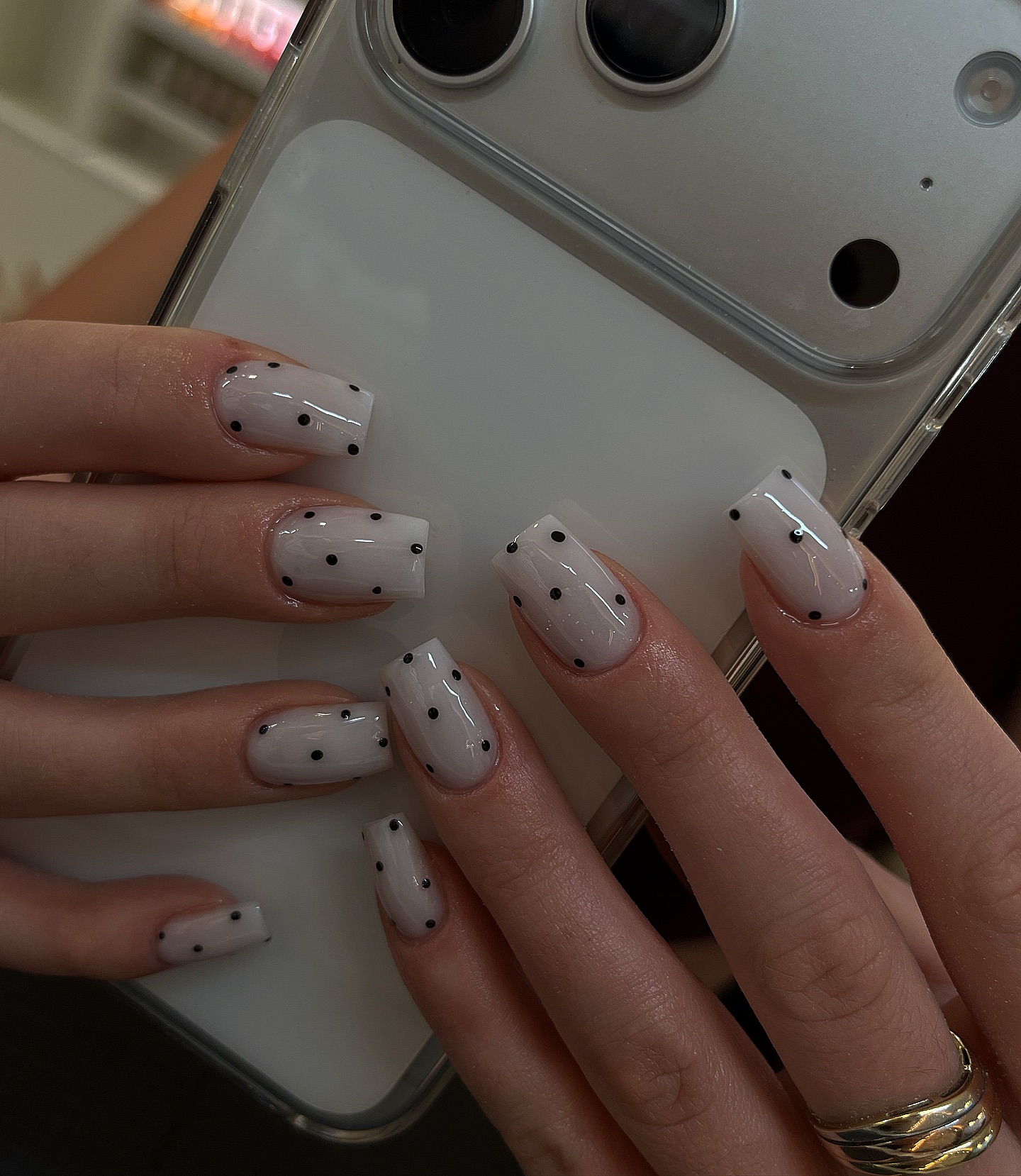 Milky white nails with scattered tiny black polka dots