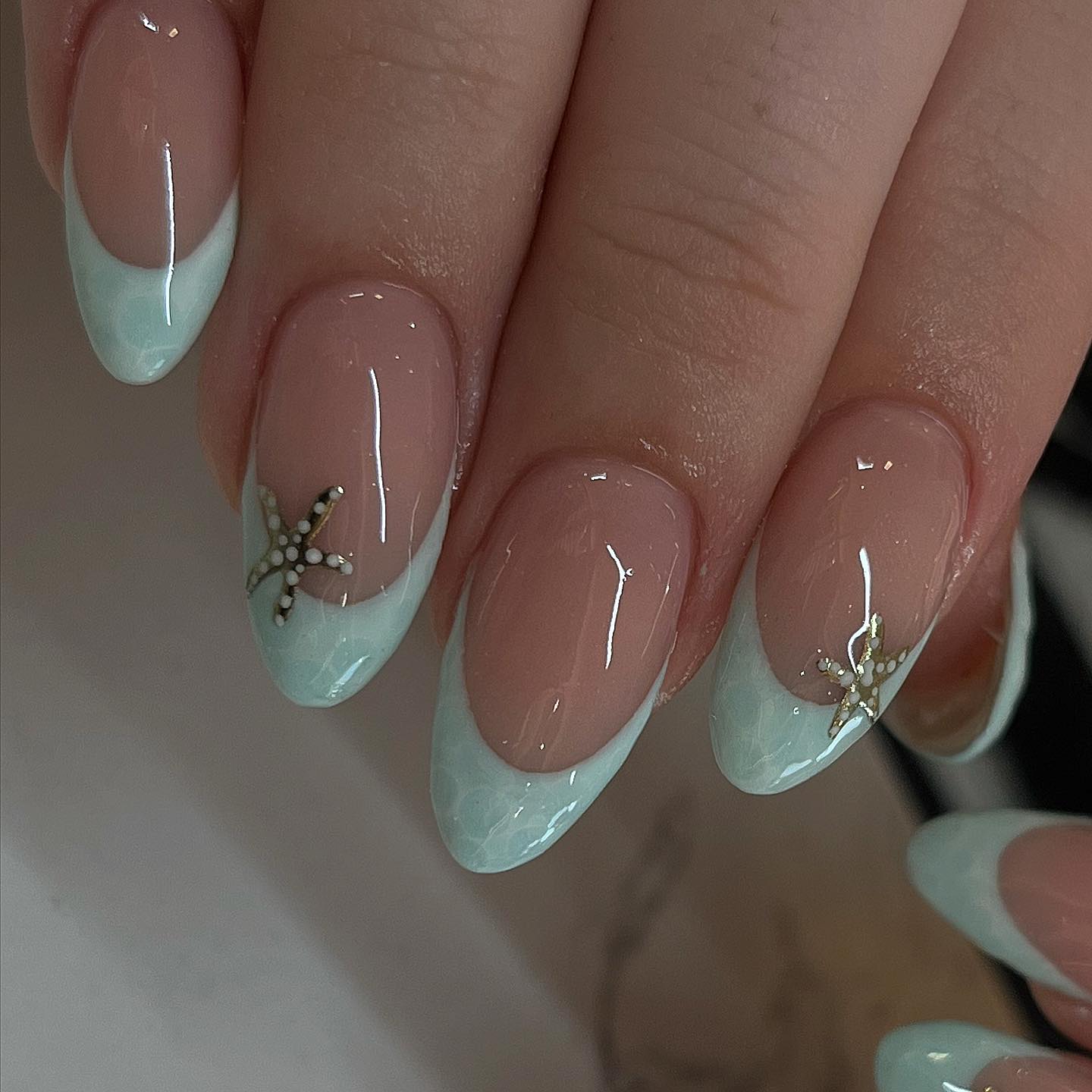 Mint green French tips with gold pearl starfish charm on nude almond nails