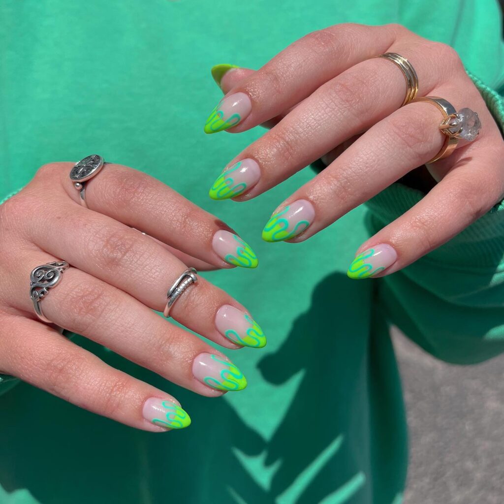 Long almond nails with neon lime green French tips and teal swirl line details on nude base
