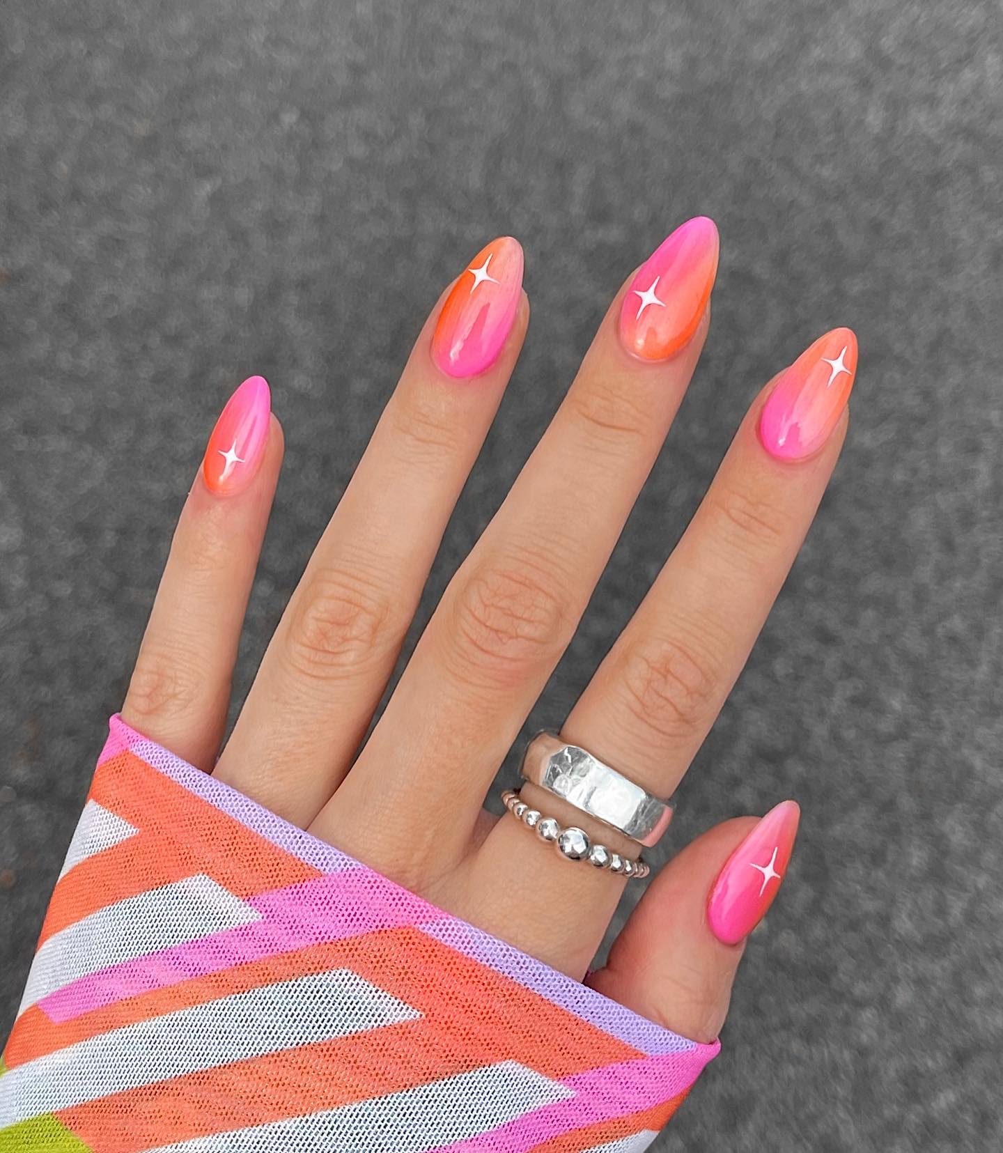 Neon pink and orange swirl nails with sparkle accents
