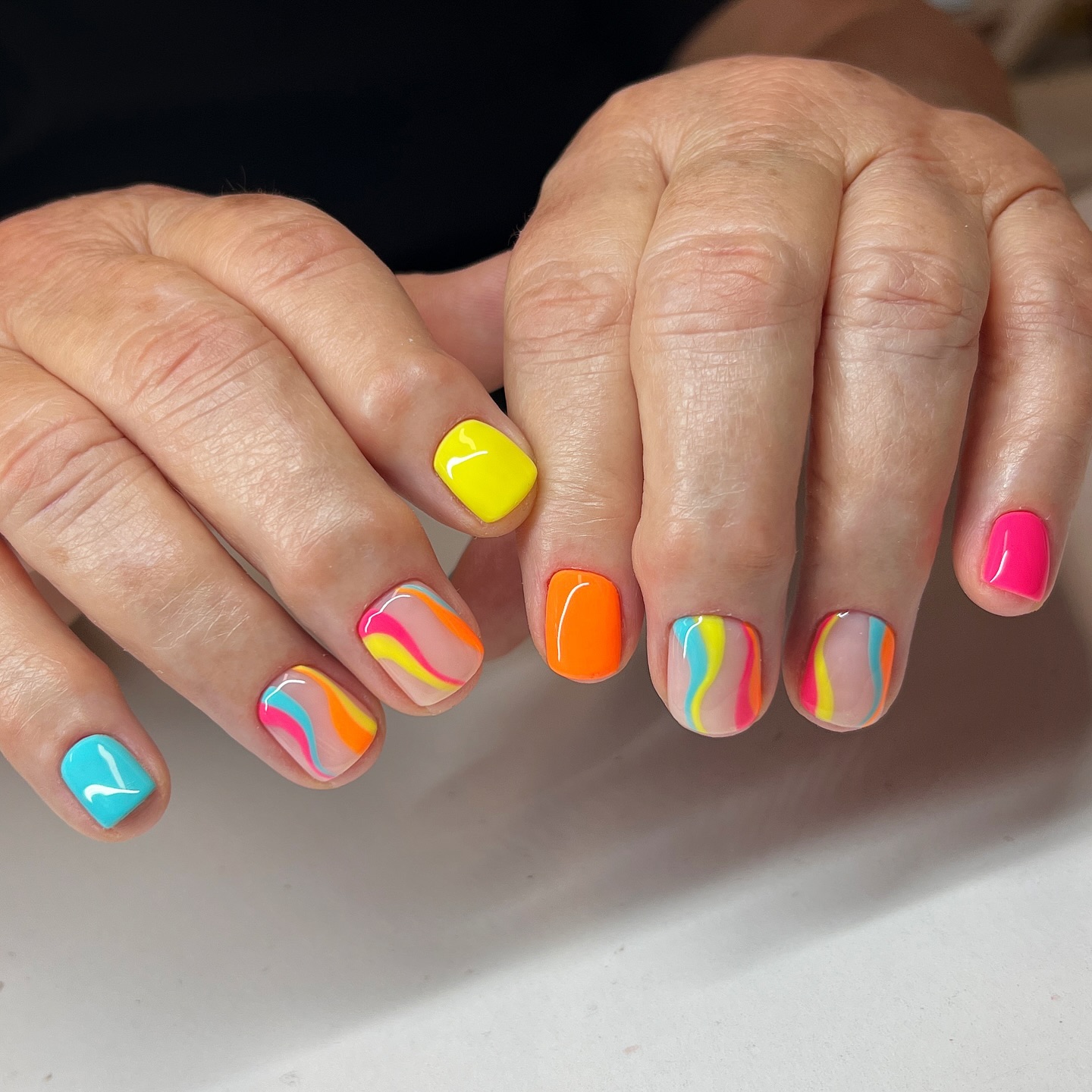 Square nails with neon rainbow swirls and solid color pops
